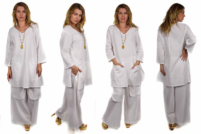 May include: A white linen tunic top with a v-neck and long sleeves. The top has two pockets on the front and a long, flowing design. The model is wearing the top with white linen pants.