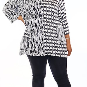May include: A black and white patterned blouse with a button fastening. The blouse features a zebra-like pattern on one side and a polka dot pattern on the other. The model is wearing black jeans and clear heeled sandals.