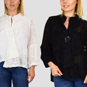 May include: Two women are wearing long-sleeved jackets with a floral design. The jacket on the left is white and the jacket on the right is black. Both jackets have a single button closure.