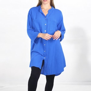 May include: A long-sleeved, blue button-down shirt with a single pocket on the left chest. The shirt is made of a soft, textured fabric and has a relaxed fit.