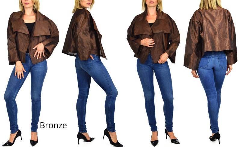 May include: A bronze-colored jacket with a draped collar and long sleeves. The jacket is worn by a model who is wearing blue jeans and black heels. The word "Bronze" is written in white text below the model.
