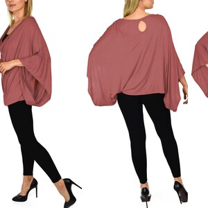 K&ouml;nnte beinhalten: Ein locker sitzendes, lang&auml;rmliges Oberteil in Mauve mit einem Rollkragen und einer Schl&uuml;ssellochausschnitt am R&uuml;cken. Das Oberteil wird mit einer schwarzen Leggings und schwarzen High-Heel-Schuhen getragen.