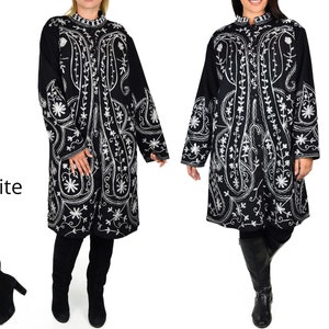 May include: Black coat with white embroidered floral and paisley designs. The coat has a mandarin collar and long sleeves. The word "White" is visible in the image. The coat is knee-length and appears to be made of a soft fabric.