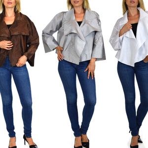 May include: Three women are wearing different colored jackets. The jackets are all the same style, with a long, flowing collar and a loose fit. The jackets are made of a soft, silky material. The women are all wearing blue jeans.