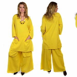 May include: A yellow two-piece outfit with a long-sleeved tunic top and wide-legged pants. The top has a V-neck and two large pockets. The pants have two large pockets on the front and a belt.