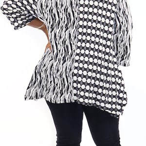 May include: A black and white patterned blouse with a loose fit and a high neckline. The blouse is worn with black jeans and clear heeled sandals.