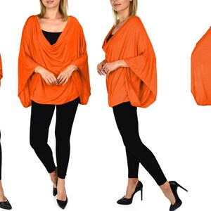 K&ouml;nnte beinhalten: Ein leuchtend orangefarbenes, locker sitzendes, lang&auml;rmeliges Oberteil mit einem Schalkragen. Das Oberteil wird an vier Models gezeigt, die schwarze Leggings und hohe Abs&auml;tze tragen.