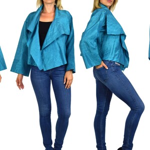 May include: A turquoise blue jacket with a draped collar and long sleeves. The jacket is made of a silky fabric and has a relaxed fit.