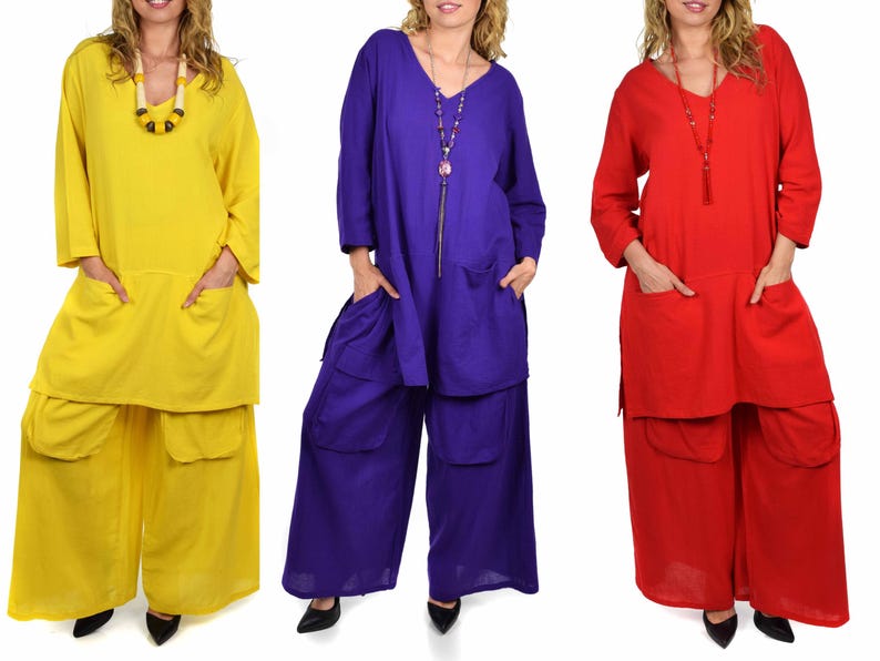 May include: Three women are wearing matching outfits with long sleeves and pants. The outfits are in three different colors: yellow, purple, and red. The outfits have pockets on the front and back.