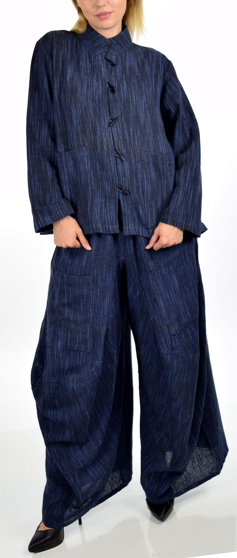 May include: A blue linen jacket with a mandarin collar and a row of buttons down the front. The jacket is paired with matching blue linen pants.