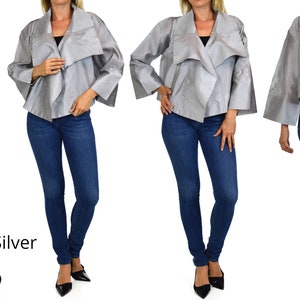 May include: A silver jacket with a draped collar and wide sleeves. The jacket is shown on a model wearing blue jeans and black heels. The word "Silver" is written in white text below the model.