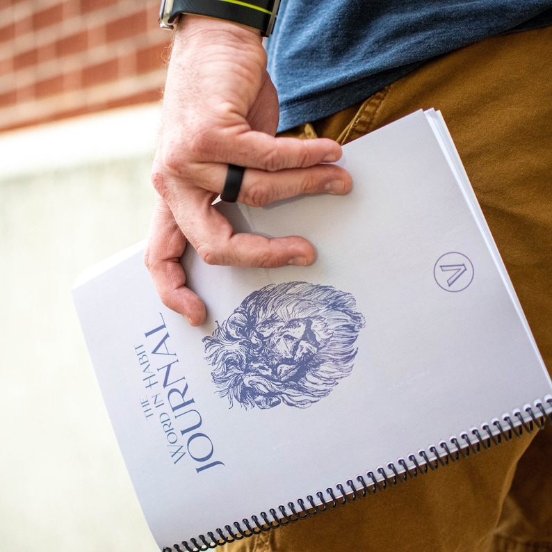 May include: A white journal with a blue lion illustration and the text "WORD IN HABIT JOURNAL" on the cover. The journal has a black spiral binding.