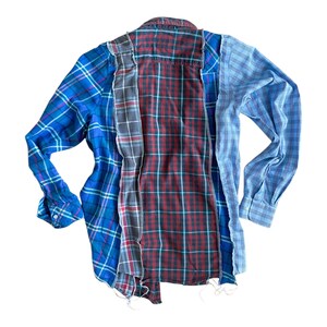Peut inclure: Une chemise en flanelle &agrave; carreaux bleus, rouges et gris avec des bords effiloch&eacute;s. La chemise est faite de plusieurs morceaux de tissu cousus ensemble.