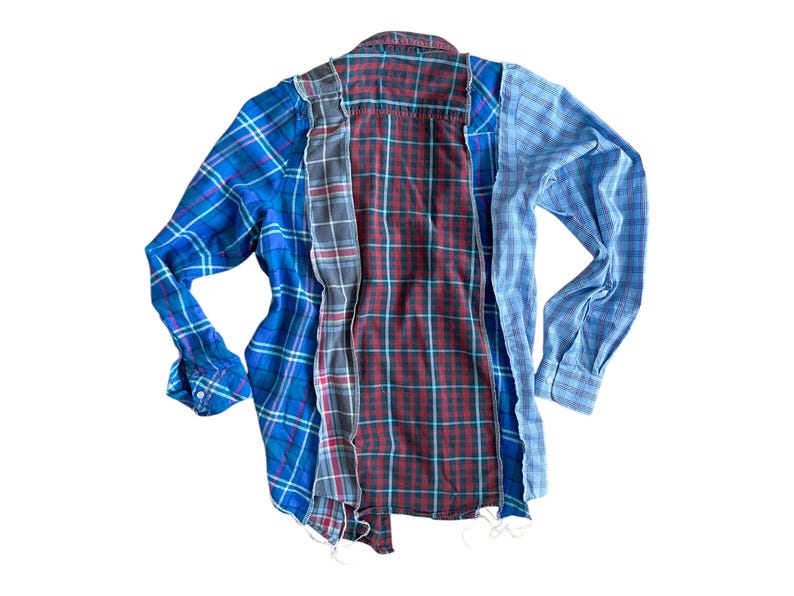 Peut inclure: Une chemise en flanelle &agrave; carreaux bleus, rouges et gris avec des bords effiloch&eacute;s. La chemise est faite de plusieurs morceaux de tissu cousus ensemble.