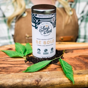 May include: A silver tin of loose leaf black tea with the words "Lend a Leaf Tea Company" and "Be Bold" printed on the label. The tea is 100% organic, ethically sourced, and single estate.