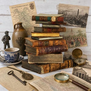 Puede incluir: Una pila de libros antiguos encuadernados en cuero, una jarra de cerámica marrón, una taza de té con motivos azules y blancos, una figura de metal, una llave de latón con un medallón, una lupa y láminas de papel vintage con mapas y escenas.