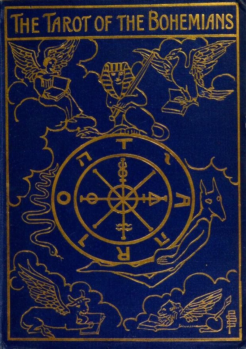 以下が含まれることがあります： 金色の文字で「The Tarot of the Bohemians」と記された濃紺のブックカバー。中央には車輪のシンボルが描かれ、その周囲をスフィンクス、蛇、そして雲の中にいる4体の翼のある人物の金色の線画が囲んでいます。