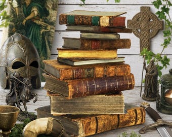 May include: A stack of antique leather-bound books sits centrally, surrounded by a metal helmet, a small knight figurine, a metal chalice, a curved horn, a sword, a Celtic cross wall plaque, and a small lantern, all arranged on a wooden surface.