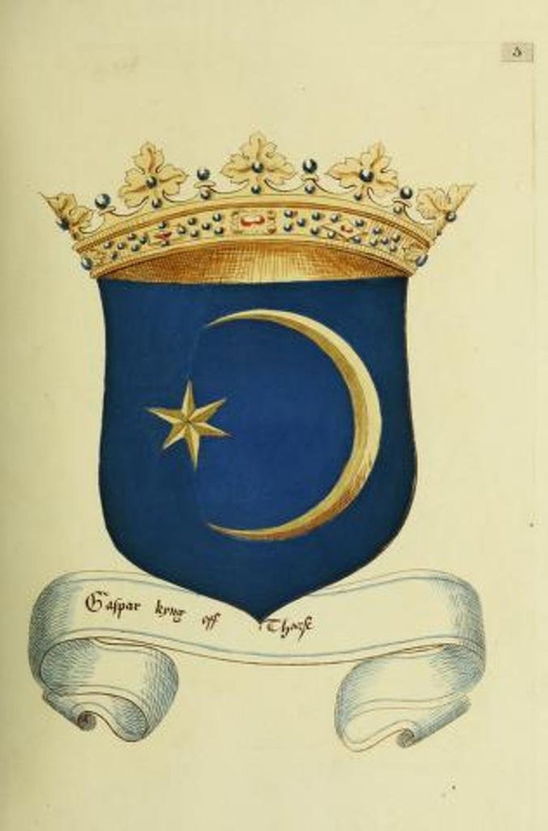 May include: A heraldic shield featuring a blue field with a gold crescent moon and a gold star. The shield is topped with an ornate gold crown and sits above a white scroll banner with the black text "Gaspar kyng off Thars".