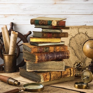 May include: A vertical stack of eight antique leather-bound books with worn covers and gold-gilded edges. The collection includes various sizes and colors, resting on a surface alongside a brass magnifying glass, a telescope, a compass, and a globe.