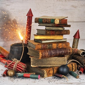 Op de afbeelding: Een stapel antieke, in leer gebonden boeken omringd door diverse vuurwerkartikelen, waaronder rode raketten, een brandend vuurwerk in een zwarte ton, een zwarte bolvormige bom en bundels rode dynamietstaven met zichtbare lonten en vonken.