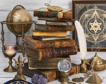 May include: A stack of antique books topped with a brass compass, a globe, a lit candle in a purple glass holder, a small statue, a crystal ball, a magnifying glass, a white feather quill, a brass incense burner, and a blue velvet pouch.