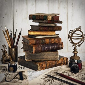 Può includere: Una pila di libri antichi rilegati in pelle usurata si trova al centro, circondata da quattro penne calligrafiche in un portapenne metallico, due piccoli calamai, una sfera armillare in ottone e pergamene decorative con scritte a inchiostro nero.