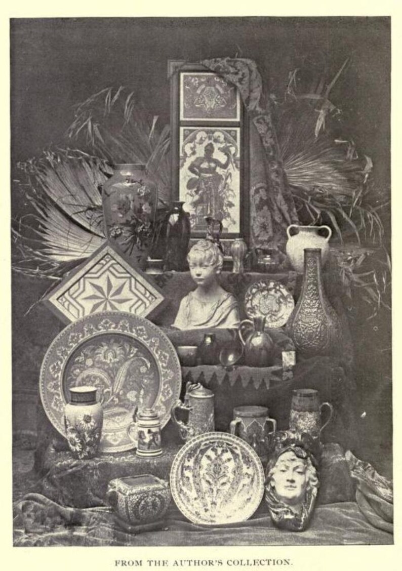 May include: A monochromatic collection of decorative objects including ceramic vases, ornate plates, a central bust of a child, a rectangular framed panel with a figure, and a sculpted face mask. The text at the bottom reads FROM THE AUTHOR'S COLLECTION.