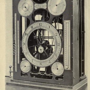 May include: A black metal tide-predicting machine featuring a large central circular dial with numbers one through twelve, surrounded by four smaller circular dials, two vertical scales, and a hand crank on the left side, labeled Plate X.