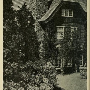 May include: A black and white photo of a house with a stone chimney and a path leading up to the front door. The house has a gabled roof and several windows. There are trees and bushes surrounding the house.