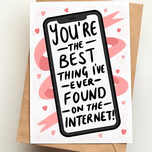 Op de afbeelding: Een wenskaart met een bruine envelop. De kaart toont een smartphone-afbeelding met de tekst "You're the best thing I've ever found on the internet!" in het zwart. Roze harten en een roze lint accentueren de witte achtergrond.