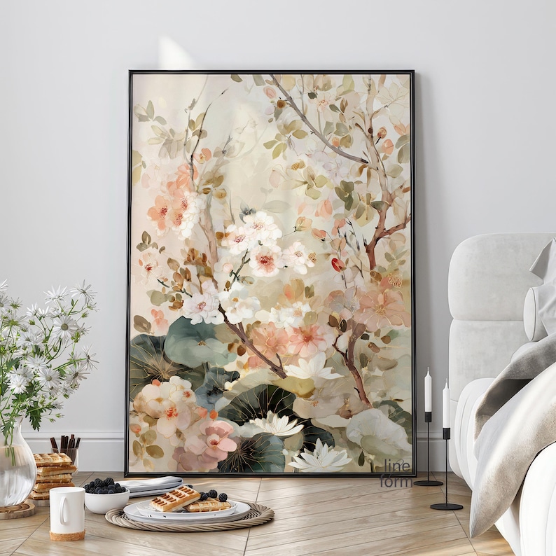 May include: A framed floral art print featuring a watercolor painting of white, peach, and pink flowers. The artwork includes green leaves and branches against a soft, neutral background. The black frame adds a modern touch.