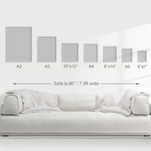 Pu&ograve; includere: Un divano bianco con una serie di stampe artistiche incorniciate di varie dimensioni, tra cui A2, A3, 10"x12", A4, 8"x10", A5 e 5"x7". Il divano &egrave; largo 229 cm. Le stampe sono esposte su una parete bianca.