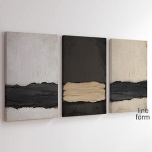 May include: Three abstract paintings with a minimalist design. The paintings are in shades of white, black, and beige. The paintings are hung on a white wall.