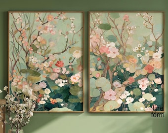 May include: Two framed floral art prints. The artwork features a soft color palette of pink, white, and green blossoms against a light green background. The prints are in wooden frames and are displayed on a green wall.