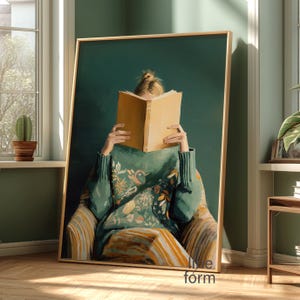 Puede incluir: Una impresión artística enmarcada representa a una persona sentada en una silla, absorta en la lectura de un libro. La persona lleva un suéter verde con motivos florales. La obra tiene un fondo verde oscuro y un marco dorado. La silla tiene un patrón de rayas.