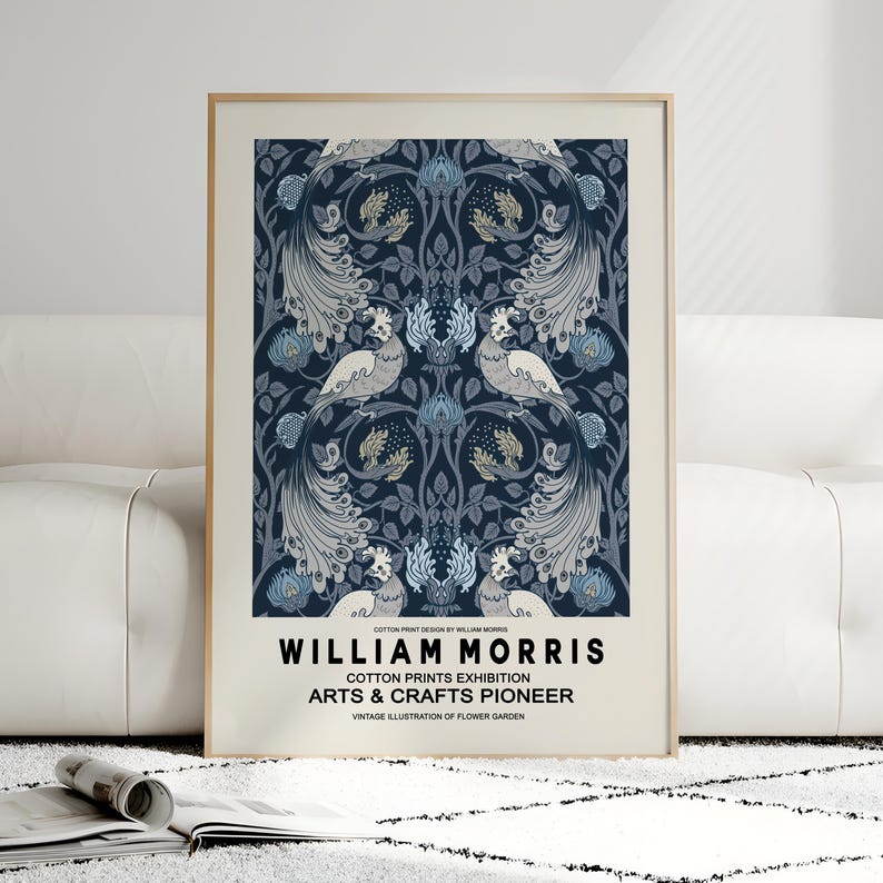 Pu&ograve; includere: Una stampa incorniciata con un design simmetrico con uccelli ed elementi floreali nei toni del blu, grigio e crema. La stampa include il testo "WILLIAM MORRIS" e "COTTON PRINTS EXHIBITION ARTS & CRAFTS PIONEER".