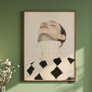 Puede incluir: Impresi&oacute;n art&iacute;stica enmarcada que presenta un retrato de una persona con los ojos cerrados, vestida con un jersey de cuello alto blanco con un patr&oacute;n de diamantes negros. La obra de arte est&aacute; enmarcada en un marco de madera.