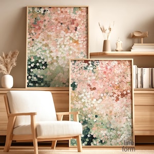 May include: Two framed abstract art prints with a dot pattern in pink, green, and white hues. The artwork is displayed in a room with a wooden chair and a wooden cabinet. The prints have a light wood frame.