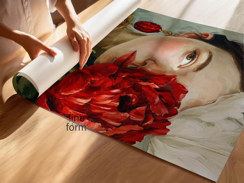 Puede incluir: Una persona desenrolla una impresi&oacute;n art&iacute;stica que presenta un retrato de una persona con una gran flor roja. La obra de arte tiene un estilo pict&oacute;rico, con un enfoque en el rostro y el rojo vibrante de la flor. La impresi&oacute;n est&aacute; sobre una superficie de madera.