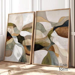 Puede incluir: Dos obras de arte abstractas enmarcadas. La obra presenta un diseño en capas con tonos neutros de beige, marrón, verde y blanco. Los marcos son de madera clara. Las obras de arte están apoyadas contra una pared.