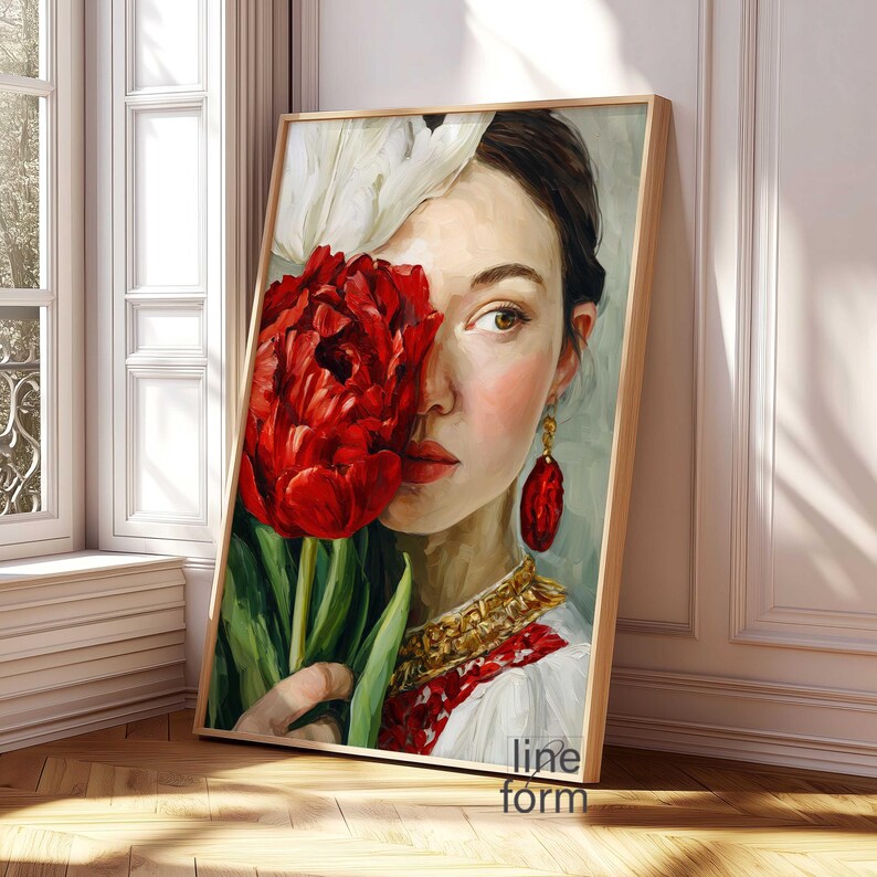 Puede incluir: Una impresi&oacute;n art&iacute;stica enmarcada que presenta un retrato de una mujer con una flor roja que le cubre parcialmente la cara. La mujer lleva un vestido blanco con bordados rojos y joyas doradas. La obra de arte se exhibe en una habitaci&oacute;n con una ventana.