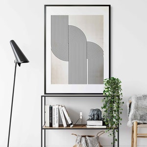 May include: A black framed print with a geometric design of overlapping black lines on a beige background. The print is displayed on a black metal shelf with books and a small elephant figurine.
