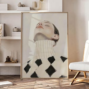 Puede incluir: Una impresi&oacute;n art&iacute;stica enmarcada que presenta un retrato de una persona con los ojos cerrados, con un su&eacute;ter de cuello alto color crema con un patr&oacute;n de diamantes negros. La obra de arte est&aacute; enmarcada en madera.