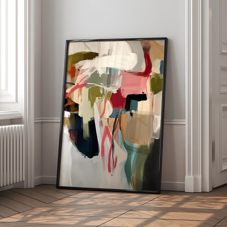 Puede incluir: Impresi&oacute;n art&iacute;stica abstracta en un marco negro. La obra presenta una composici&oacute;n colorida con pinceladas en tonos rosa, rojo, verde, azul y beige. La pintura se apoya en una pared blanca y un suelo de madera.