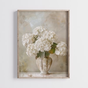 Pode incluir: Um buquê de hortênsias brancas em um vaso de cerâmica creme com uma superfície texturizada. As flores são dispostas em um estilo vintage sobre um fundo bege claro.