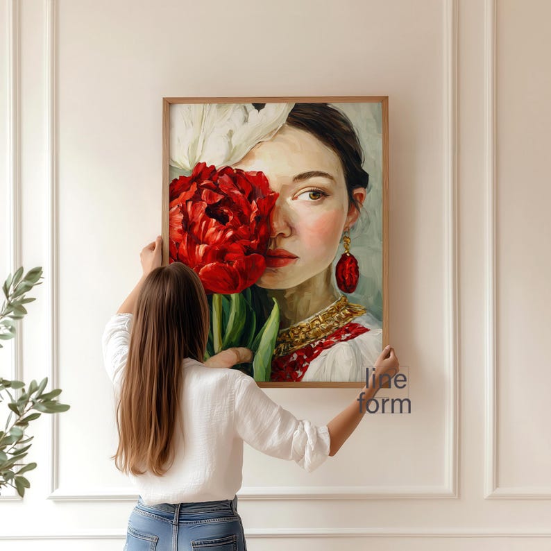 Puede incluir: Un retrato enmarcado de una mujer sosteniendo una gran flor roja, que oscurece parcialmente su rostro. La obra de arte presenta a una mujer con pendientes rojos y un vestido bordado blanco y rojo. El marco es de color marr&oacute;n claro. El texto "line form" es visible.