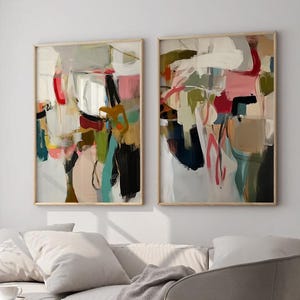 Puede incluir: Dos obras de arte abstractas enmarcadas. Cada una presenta una mezcla de colores, incluyendo rojo, rosa, verde y azul, con fondos beige y blanco. La obra de arte es de estilo moderno, con pinceladas visibles y un aspecto texturizado.