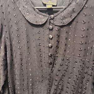 May include: Black dress with a Peter Pan collar and floral embroidery. The dress has a button-down front and long sleeves. The fabric is semi-sheer, and the dress is hanging on a black hanger. The brand tag is visible at the neckline.