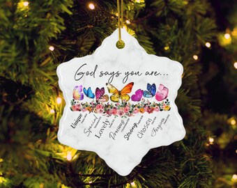 May include: A white, star-shaped Christmas ornament with a marble design. The ornament features colorful butterflies and the text "God says you are..." with words like "Unique" and "Chosen" below. A gold string is attached for hanging.